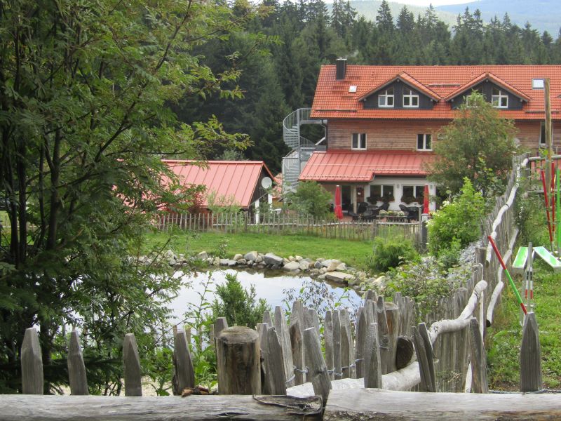 Hotel mit Terrasse, vorne der Teich im Freilauf